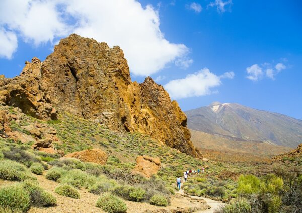 hikers between the roques de garcia in teide national park, pico de teide in the background