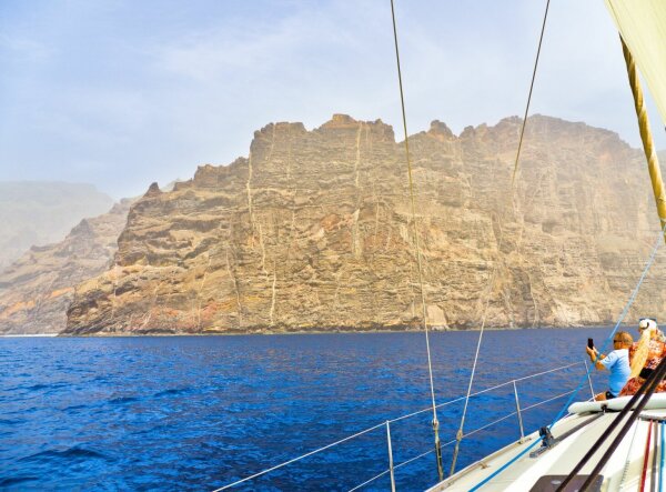 los gigantes rocks on tenerife, seen from a sailing boat, fragments of the boat with people taking photos etc. on the right side