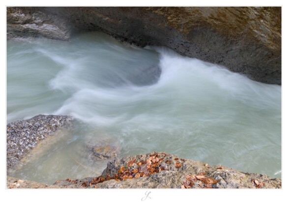 Long exposure of a mountain river that flows from the left to the right. The long exposure creates a very soft texture on the water surface. Some vortexes around rocks occur in white, the rest of the water has a touch of green. The banks are of large, steep rocks at the top and flat rocks with some brown leafs at the bottom of the landscape take.

AI disclaimer: Using my work, its meta data, written or derived description to create media with or train AI based systems is prohibited.