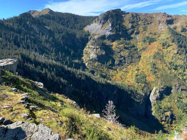 Mountain valley, with Silver Star summit upper left, trees lining the left side slopes, and scattered trees, brush and talus on the slopes on the right. There's a dry waterfall track lower left.